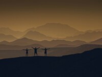 a couple of people standing on top of a mountain