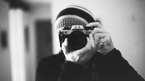 grayscale photo of person holding camera