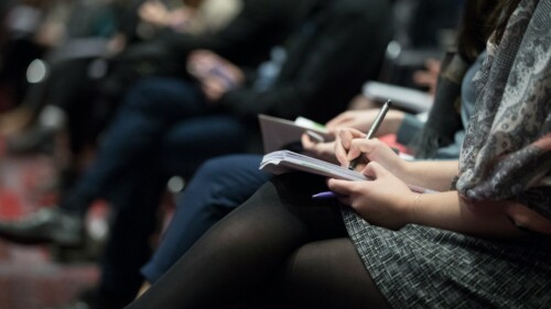 selective focus photography of people sitting on chairs while writing on notebooks